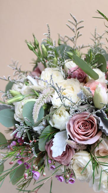 A beautifully arranged bouquet featuring soft pink and white roses, complemented by pale green eucalyptus leaves and delicate sprigs of lavender and dusty miller. The flowers are tightly clustered, sh